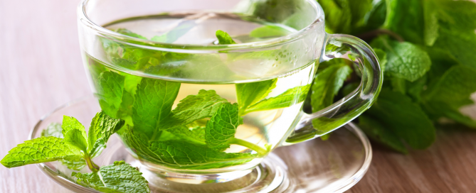 glass teacup filled with mint leaves and mint tea